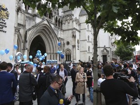 Supporters of critically ill baby Charlie Gard outside the High Court in London after his parents Connie Yates and Chris Gard spoke Monday, July 24, 2017. The parents of critically ill baby Charlie Gard wept as they dropped their legal bid Monday to send him to the United States for an experimental medical treatment, acknowledging that the window of opportunity to help him had closed.  (AP Photo/Caroline Spiezio)