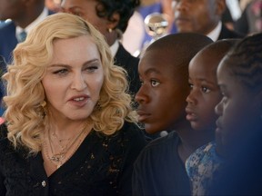 FILE- In this July 11, 2017 file photo, Madonna, left, sits with her adopted children David, Stella and Mercy, at the opening of The Mercy James Institute for Pediatric Surgery and Intensive Care, located at the Queen Elizabeth Central Hospital in the city of Blantyre, Malawi. A lawyer for Madonna said Thursday July 27, 2017, that the star and her twin daughters Stella and Estere have accepted damages form the publisher of the Mail Online website over an article that was a "serious invasion of privacy." Madonna sued Associated Newspapers over a January story giving details of her adoption of the 4-year-old twins from Malawi.  (AP Photo Thoko Chikondi, File)