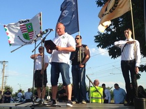 A member of the National City Federation, Attila Szabo, speaks during the inaugural event of Force and Determination, a new extremist alliance formed by three small far-right groups in Vecses, on the outskirts of Budapest, Hungary, Saturday July 8, 2017, as people behind hold flags of the three groups which formed the alliance.  The Force and Determination alliance says its main goal is to fight liberalism, which members say has made Europe "unliveable and indefensible." (AP Photo/Pablo Gorondi)