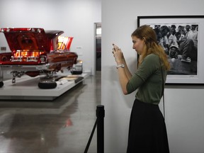 In this Thursday, June 29, 2017, photo, Amy Stringfellow, visiting form Australia, takes pictures of "Our Family Car," a customized 1950 Chevrolet Sedan during an exhibition titled "The High Art of Riding Low" at the Petersen Automotive Museum in Los Angeles. (AP Photo/Jae C. Hong)