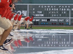 The grounds crew removes the tarp, completely filled with rain water, after a heavy storm passed over prior to a baseball game between the Boston Red Sox and Toronto Blue Jays at Fenway Park in Boston, Tuesday, July 18, 2017. The start of the game was delayed for about an hour. (AP Photo/Charles Krupa)