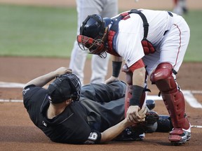 Boston Red Sox catcher Christian Vazquez aids home plate umpire Chris Segal after he was accidentally hit on the head by Toronto Blue Jays' Josh Donaldson's bat during the first inning of a baseball game at Fenway Park in Boston, Monday, July 17, 2017.