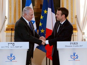 French President Emmanuel Macron (R) and Israeli Prime Minister Benjamin Netanyahu (L) shake hands at the end of a joint press conference at the Elysee Palace in Paris, on July 16, 2017.