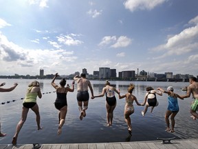 People dive into the Charles River during the "City Splash" event, Tuesday, July 18, 2017, in Boston. For the fifth year in a row, intrepid swimmers get a rare chance to beat the summer heat with a dip in the once notoriously filthy Charles River, where conservationists are working to build a permanent swim park. (AP Photo/Elise Amendola)