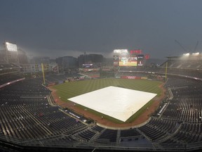 The tarp lies on the field as the start of the baseball game between the Washington Nationals and the New York Mets is delayed due to inclement weather, Wednesday, July 5, 2017, in Washington. (AP Photo/Nick Wass)