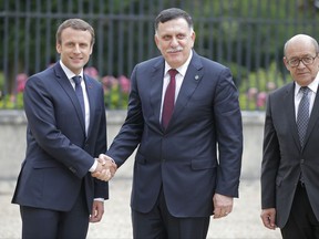 France's President Emmanuel Macron, left, welcomes Libya's Prime Minister Fayez al-Sarraj of the U.N.-backed government at the Chateau of the La Celle-Saint-Cloud, west of Paris, France, Tuesday, July 25, 2017. President Emmanuel Macron is hosting a meeting of the two main rival leaders of chaotic Libya, trying to play peacemaker in a country where the stakes are high for both Europe and Africa. Left, French Minister of Foreign Affairs Jean-Yves Le Drian. (AP Photo/Michel Euler)