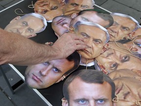 Masks of French President Emanuel Macron and Israeli Prime Minister Benjamin Netanyahu lay on a table as a pro-Palestinian activist takes one away during a gathering to protest Israeli Prime Minister's visit to France in Paris, Saturday, July 15, 2017. French President Emanuel Macron's invited on Sunday Israeli Prime Minister Benjamin Netanyahu for bilateral talks and a commemoration of a mass deportation of French Jews to Nazi camps 75 years ago. (AP Photo/Michel Euler)