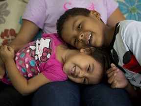 In this June 22, 2017 photo, Carlita Perez, 3, from El Salvador, and Josue Funez Cruz, 7, from Honduras, play together on the lap of Josue's sister Laura, 14, in the two-bedroom apartment the families share in the Iztapalapa district of Mexico City. Even as it has cracked down on illegal migration along its southern border, Mexico has come under pressure to welcome more refugees. Increasingly, word has made it back to Central America that it's easier to resettle in Mexico. (AP Photo/Rebecca Blackwell)