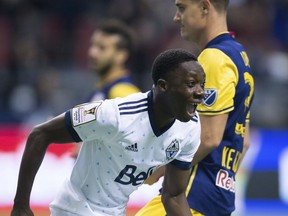 FILE - In this March 2, 2017, file photo, Vancouver Whitecaps' Alphonso Davies, front, celebrates after scoring a goal as New York Red Bulls' Aaron Long looks away during the first half of a CONCACAF Champions League soccer quarterfinal in Vancouver, British Columbia. Davies was born in a Ghanaian refugee camp and immigrated to Canada when he was five. Now the 16-year-old Vancouver Whitecaps midfielder is the youngest national team player in Canada's history approaching the Gold Cup.  (Darryl Dyck/The Canadian Press via AP, File)