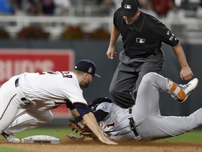 Minnesota Twins second baseman Brian Dozier, left, tags out Detroit Tigers' Jose Iglesias, right, who tried to stretch a single into a double during the ninth inning of a baseball game Saturday, July 22, 2017, in Minneapolis. Second base umpire Jeff Kellogg moves in to make the call. The Twins won 6-5. (AP Photo/Tom Olmscheid)