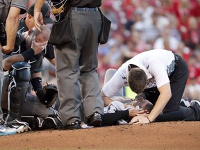Diamondbacks catcher covers his face Chris Herrmann, left, covers his face as Diamondbacks starting pitcher Robbie Ray, bottom right, is checked on by a trainer after Ray was hit on the head by a ball back to the mound by St. Louis Cardinals' Luke Voit during the second inning of a baseball game Friday, July 28, 2017, in St. Louis. Ray left the game. (AP Photo/Jeff Roberson)