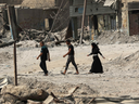 Iraqis walk through the ruins of Mosul a few days after the government announced its liberation from ISIL fighters.