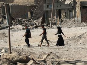 Iraqis walk through the ruins of Mosul a few days after the government announced its liberation from ISIL fighters.