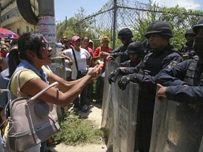 Relatives of inmates confront state police securing the area around the state prison in Acapulco, Mexico, Thursday, July 6, 2017. Fighting erupted between rival gangs inside the state prison before dawn Thursday, and more than 25 inmates were killed and three wounded, officials in the Pacific resort said. (AP Photo/Bernandino Hernandez)