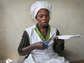 In this photo taken Thursday, July 13, 2017, a worker cuts locally made biodegradable sanitary pads known as Makapads, made from waste paper with papyrus as the absorbent, that sell for half the price of imported pads, at a factory in Kampala, Uganda. Menstrual hygiene has emerged as a serious, and often emotional, subject in Africa, where some experts say governments must supply free sanitary pads to girls who are often at risk of dropping out of school because of embarrassment. (AP Photo/Stephen Wandera)