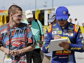 Chase Elliott, right, signs an autograph for a fan in the garage area before NASCAR Cup auto racing practice at Daytona International Speedway, Thursday, June 29, 2017, in Daytona Beach, Fla. (AP Photo/John Raoux)