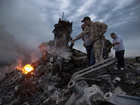 FILE - In this Thursday, July 17, 2014 file photo, people inspect the crash site of a passenger plane near the village of Grabovo, Ukraine. Any suspects in the downing of Malaysia Airlines flight 17 over Ukraine in 2014 will be prosecuted in the Netherlands, the Dutch government announced Wednesday July 5, 2017. (AP Photo/Dmitry Lovetsky, File)