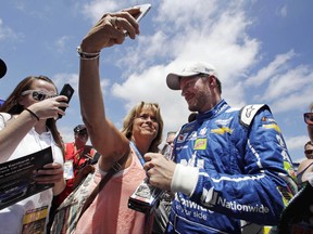 Mary Goodnow, of Londonderry, N.H., tries to snap a selfie with driver Dale Earnhardt Jr. while he signs autographs following a practice session for Sunday's Cup Series 301 auto race at the New Hampshire Motor Speedway in Loudon, N.H., Saturday, July 15, 2017. (AP Photo/Charles Krupa)