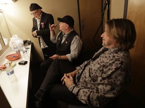 In a photo taken Thursday, July 20, 2017, members of The Hit Men, from left, Russ Velazquez, Mark Feinberg and Steve Murphy converse while hanging out in the dressing room before performing at the Axelrod Performing Arts Center in Deal Park, N.J.  Five years after hitting the road to capitalize on the popularity of Broadway's "Jersey Boys," a group of musicians who played with Frankie Valli and the Four Seasons and other groups are still at it. The Hit Men have played hundreds of shows across the country and are releasing a new song, "You Can't Fight Love." They've taken advantage of the lucrative market for pop music nostalgia with a show that explores their past associations with some of music's biggest names. (AP Photo/Julio Cortez)