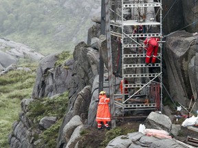 Workers try to raise a damaged boulder to repair the penis-shaped Trollpikken rock formation in Eigersund municipality, Rogaland, southern Norway, Friday, July 7, 2017. The rock, a popular tourist attraction, was found badly damaged. Joggers discovered Saturday, June 24, that the Trollpikken rock formation had cracked and noted drilling holes in the rock _ something that experts say strongly suggests the rock was deliberately vandalized. (Torstein Boe/NTB scanpix via AP)