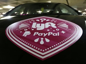 FILE - In this March 31, 2016, a Lyft ride-hailing service logo is displayed on a vehicle at Seattle-Tacoma International Airport in Seattle. Lyft is setting up its own unit to develop autonomous vehicle technology, but its approach will be different from other companies and partnerships working on self-driving cars. The San Francisco-based ride-hailing service says it will open its network, inviting automakers and tech companies to use it to haul passengers and gather data. . (AP Photo/Ted S. Warren, File)
