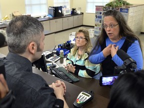 FILE - In this Sept. 1, 2015, file photo, Rowan County Clerk Kim Davis, right, talks with David Moore following her office's refusal to issue marriage licenses at the Rowan County Courthouse in Morehead, Ky. On Friday, July 21, 2017, a federal judge has ordered Kentucky taxpayers to pay more than $220,000 in attorneys' fees for the elected county clerk who caused a national uproar by refusing to issue marriage licenses to same-sex couples. (AP Photo/Timothy D. Easley, File)