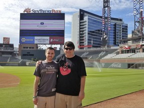 In this 2017 photo provided by Frank Gennario Jr., Frank Gennario Jr. and his son, Tony, pose at SunTrust Park in Atlanta.  Frank Gennario lost his father to bone cancer when he was 16, and he clings tightly to memories of their days at Yankee Stadium. When Frank's only son was nearing the same age, it became critical to him that they build those same ballpark memories. So the pair set a goal: see their beloved Arizona Diamondbacks play in every big league park. Ten years later, they have completed their quest. (Frank Gennario Jr. via AP)