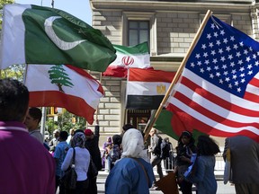 FILE - In this Sunday, Sept. 25 2016, photo, marchers carry the national flags of Pakistan, top left, Lebanon, bottom left, Iran, top center, Egypt, bottom center and the American flag, right, during the Muslim Day Parade on Madison Avenue in New York. U.S. Muslims said they have experienced widespread suspicion about their faith in the first months of Donald Trump's presidency, but also have received more support from individual Americans, and remain hopeful they can eventually be fully accepted in American society, according to a Pew Research Center report released Wednesday, July 26, 2017. (AP Photo/Craig Ruttle, File)