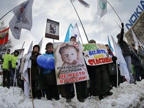 FILE - In this Saturday, March 2, 2013 file photo, demonstrators hold posters reading "There is no place for juvenile justice in Russia," "I want all children be happy" during a rally in Moscow to support the ban on U.S. adoptions of Russian children. More than four years after it was imposed, Russia's ban on adoptions by Americans is back in the news, rekindling frustration and sadness among some of those affected by it. (AP Photo/Alexander Zemlianichenko)