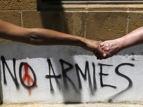 FILE - In this Saturday, May 27, 2017, file photo, Greek and Turkish Cypriots hold hands as they gather to call to the rival leaders of the two communities to "Unite Cyprus Now" at the Ledras main crossing point inside the U.N buffer zone that divided the Greek and Turkish Cypriots controlled areas, in Nicosia, Cyprus. The UN Security Council unanimously approved a resolution encouraging rival Greek Cypriots and Turkish Cypriots "to sustain their commitment" to reunifying the divided Mediterranean island following the collapse of talks earlier in July. (AP Photo/Petros Karadjias, File)