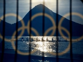 FILE - In this Aug. 7, 2016, file photo, rowers are seen through a screen decorated with the Olympic rings as they practice at the rowing venue in Lagoa at the 2016 Summer Olympics in Rio de Janeiro, Brazil. The Olympic Channel, a new Olympic-themed television network makes its debut on Saturday, July 15. (AP Photo/David Goldman, File)