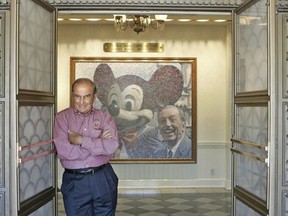FILE - In this July 11, 2005 file photo, Imagineering Vice Chairman and Principal Creative Executive Martin "Marty" Sklar poses in front of a picture of Mickey Mouse and Walt Disney at Disneyland in Anaheim, Calif. Sklar, one of the central figures behind Disney's theme parks around the world, has died.  Sklar had a role in the opening of every Disney park, starting with the original Disneyland in 1955. A Disney statement said he died Thursday, July 27, 2017, at his Hollywood Hills home at age 83. (AP Photo/Jae C. Hong, File)