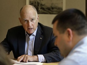 FILE - In this July 7, 2017, file photo, California Gov. Jerry Brown discusses a bill with Chris Ferguson, right, a principal program budget analyst in Sacramento, Calif. Brown and legislative leaders released a plan Monday to extend through 2030 California's cap-and-trade program, a key piece of the state's quest to fight climate change by drastically reducing emissions from greenhouse gases. (AP Photo/Rich Pedroncelli, File)