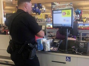 This July 22, 2017, photo provided by the City of Laurel Police Department, officer Bennet Johns buys diapers for a woman accused of shoplifting in Laurel, Md. The woman, who reportedly bought some items but did not have $15 for two packs of diapers, was given a citation for misdemeanor shoplifting. Johns, who was raised by a single mother, was touched by the woman's predicament and used his own money to buy the diapers for her toddler. (PFC Carl Johnson/City of Laurel Police Department via AP)