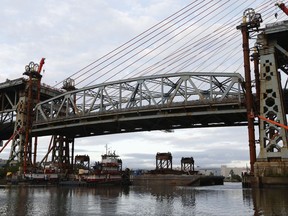 The original main span of the Kosciuszko Bridge is lowered onto two barges lashed together in Newtown Creek, Tuesday, July 25, 2017, in New York. (AP Photo/Kathy Willens)