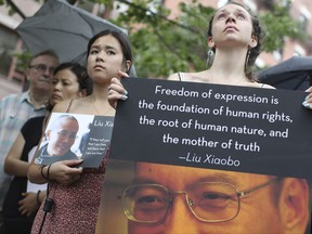Participants hold photos of Liu Xiaobo, right, and his wife Liu Xia during a vigil honoring Liu Xiaobo's legacy and to protest continued human rights abuses in China, Thursday, July 13, 2017, in New York. China's most prominent political prisoner died Thursday of liver cancer at 61. (AP Photo/Mary Altaffer)