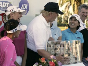 FILE - This Nov. 18, 2006 file photo shows Donald Trump, center, putting his hands on a box of money while posing for a photo with the eight golfers who qualified for the final round following the third round of the LPGA ADT Championship at the Trump International Golf Club in West Palm Beach, Fla. Also present, from left to right, are: Mi Hyun Kim, of South Korea, Natalie Gulbis and il Mi Chung, also of South Korea. The U.S. Women's Open will be played next week at a golf course in New Jersey owned by President Trump. The USGA awarded the site in 2012 and later came under pressure from women's groups and three Democratic U.S. senators to move the event because of Trump's comments about women and minorities. It's uncertain if the president will attend the tournament in Bedminster, New Jersey. (AP Photo/Lynne Sladky)