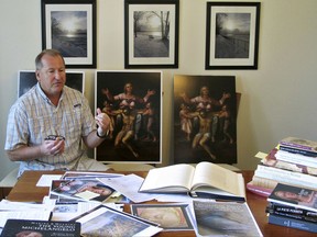 In this June 26, 2017 photo, Martin Kober displays literature and copies of a family heirloom that he believes was painted by Renaissance master Michelangelo, at his home in Tonawanda, N.Y. Kober is convinced the painting of a dying Jesus that hung above the mantel in his upstate New York childhood home is the work of Michelangelo. Getting experts to agree remains the $300 million hurdle. (AP Photo/Carolyn Thompson)