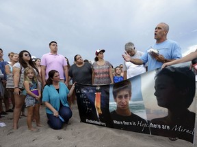 FILE - In a Tuesday, July 28, 2015 file photo, Carl Hodges, of Stuart, Fla., right, reads a prayer during a vigil for Austin Stephanos and Perry Cohen, in Stuart, Fla. , two teenagers who have been missing since they went out on a boat to go fishing from Tequesta, Fla. and never returned. U.S. District Judge William P. Dimitrouleas on Monday, July 10, 2017, lifted an injunction that kept Pamela and Philip Cohen from suing Carly Black in state court. She owned the 19-foot (6-meter) boat her son Austin Stephanos was in when he left Jupiter Inlet on July 24, 2015, with the Cohens' son Perry. (AP Photo/Lynne Sladky, File)