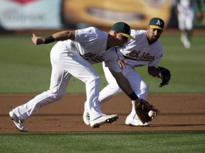 Oakland Athletics' Matt Chapman (26) cuts in front of Marcus Semien to field a grounder by Minnesota Twins' Miguel Sano during the first inning of baseball game Saturday, July 29, 2017, in Oakland, Calif. Sano was out at first.(AP Photo/D. Ross Cameron)