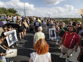 A line of demonstrators, center, in support of former University of Cincinnati police officer Ray Tensing march onto the Newport Southbank Bridge, flanked by supporters of Sam DuBose, who was fatally shot by Tensing in 2015, Monday, July 24, 2017, in downtown Cincinnati. Hamilton County Prosecutor Joseph Deters declined a third trial against Tensing in the shooting death of DuBose after two juries deadlocked on murder and voluntary manslaughter charges, claiming he does not believe the case can succeed. (AP Photo/John Minchillo)