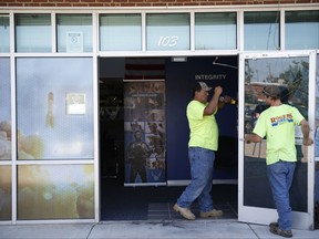 Louis Cody and Dillion McCully replace a door Tuesday, July 11, 2017, that was damaged during Monday night explosion at an Air Force recruitment center in Bixby, Okla. FBI Special Agent Jessi Rice said Tuesday that the blast is not being called terrorism because investigators have not determined a motive and have not identified a suspect.  (Ian Maule/Tulsa World via AP)
