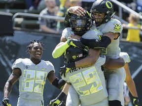 FILE - In this April 29, 2017, file photo, Oregon's Darren Carrington, center right, is congratulated by teammates Kani Benoit (29) Darrian McNeal, top right, after his third touchdown in Oregon's spring NCAA college football game at Autzen Stadium in Eugene Ore. Carrington, dismissed from Oregon two weeks ago soon after he was arrested on a misdemeanor charge of driving under the influence, has signed with Utah. (Collin Andrew/The Register-Guard via AP, File)