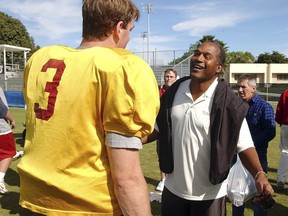 FILE - In this Dec. 28, 2002, file photo, University of Southern California quarterback Carson Palmer talks to O.J. Simpson after practice for the Orange Bowl in Davie, Fla. The two are winners of the Heisman trophy. USC head coach Todd Helton told reporters on July 27, 2017, that Simpson wouldn't be invited to watch practice or take part in any official functions at his alma mater this fall following his release from prison. (AP Photo/J. Pat Carter, File)