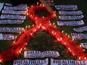 FILE - In this Dec.1, 2016 file photo, an HIV-positive Filipino lights candles around an AIDS symbol as he participates in an event in observance of World AIDS Day in Quezon city, Philippines. For the first time in the global AIDS epidemic that has spanned four decades and killed 35 million people, more than half of all those infected with HIV are on drugs to treat the virus, the United Nations said in a report released Thursday, July 20, 2017. (AP Photo/Aaron Favila, FILE)