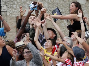 Spectators try to catch a cycling jersey distributed during the sponsors parade prior to the start of the eleventh stage of the Tour de France cycling race over 203.5 kilometers (126.5 miles) with start in Eymet and finish in Pau, France, Wednesday, July 12, 2017. (AP Photo/Christophe Ena)