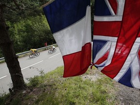 Britain's Chris Froome, wearing the overall leader's yellow jersey, passes a the Union Jack and a French flag as he speeds downhill during the seventeenth stage of the Tour de France cycling race over 183 kilometers (113.7 miles) with start in La Mure and finish in Serre-Chevalier, France, Wednesday, July 19, 2017. (AP Photo/Christophe Ena)