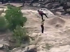 In this Sunday, July 23, 2017, image taken from video provided by the Pima County Sheriff's office, a stranded hiker is rescued from torrential flash flood waters near Tucson, Ariz. Over a dozen hikers were stranded Sunday in a scenic canyon on the outskirts of Tucson, just over a week after a flash flood killed 10 members of an extended family more than 140 miles to the north. (Pima County Sheriff via AP)