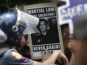 An activist holds a slogan bearing a photo of Philippine President Rodrigo Duterte during a rally in front of the Supreme Court in Manila, Philippines on Tuesday, July 4, 2017 to denounce martial law in Mindanao. The Philippine Supreme Court has upheld Duterte's declaration of martial law in the southern third of the country, dismissing petitions to nullify it.(AP Photo/Aaron Favila)