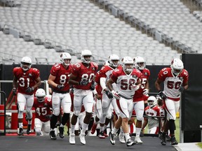 Arizona Cardinals players David Johnson (31), Troy Niklas (87), Ifeanyi Momah (80), Scooby Wright III (58) and Gabe Martin (50) lead the team onto the field during an NFL football training camp Monday, July 24, 2017, in Glendale, Ariz. (AP Photo/Ross D. Franklin)